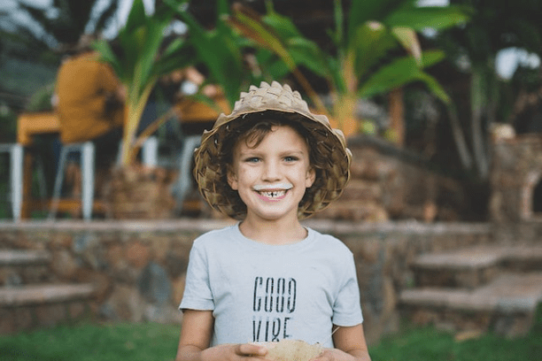 little boy in seagrass hat with a milk mustache holding half a coconut