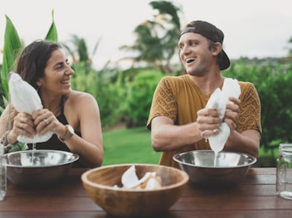a woman and man squeezing coconut milk into a bowl