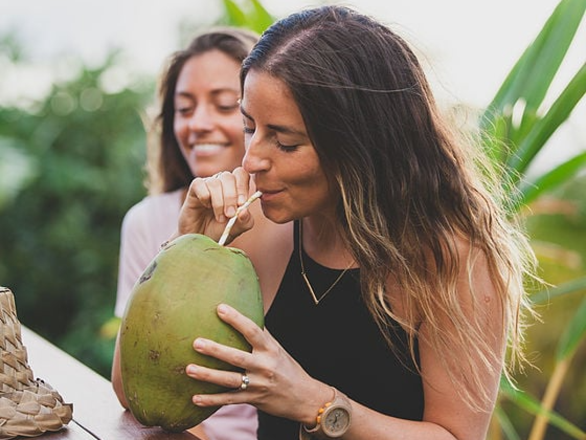 a woman drinking from coconut fruit