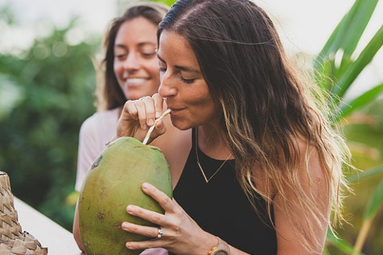 a woman drinking from coconut fruit
